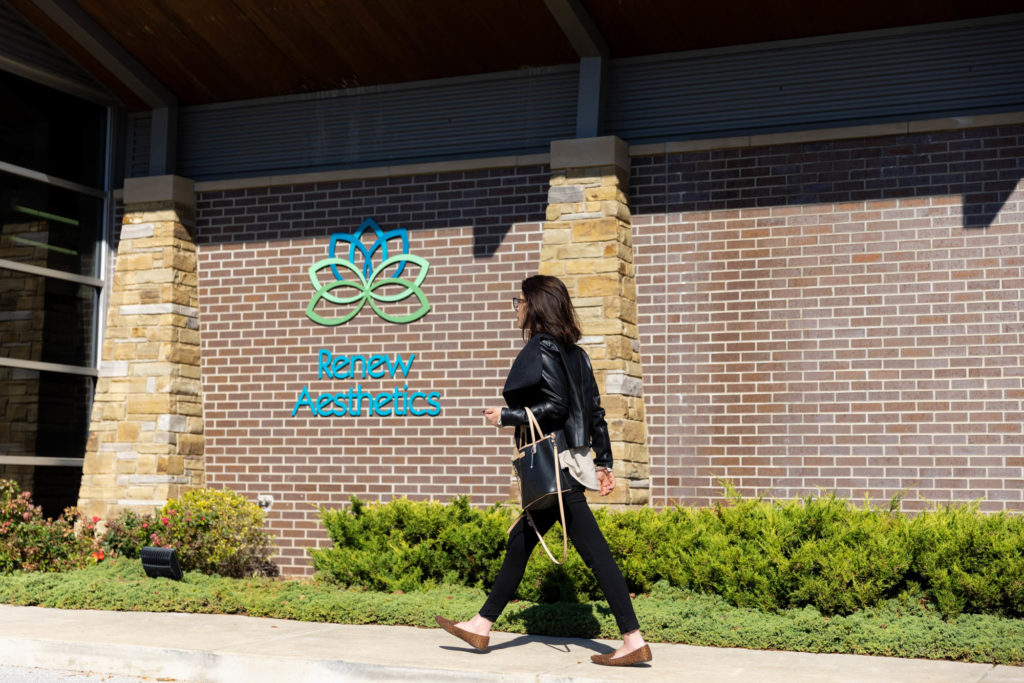 A woman in a black outfit in brown flats is walking into Renew Aesthetics, our Medical Spa in Rogers, AR.